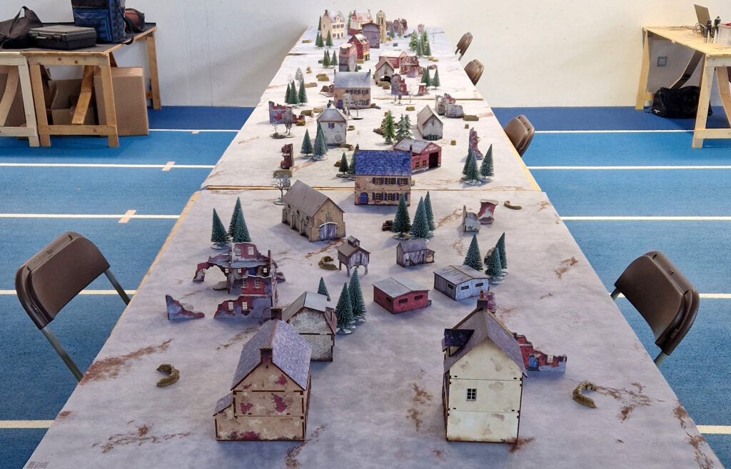 Bolt Action at the London GT - Battle of the Bulge set-up filled with MicroArt studio MDF buildings, Hornby trees, and Skytrex resin scatter terrain.