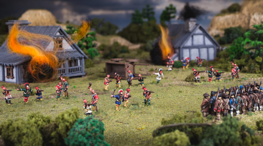 Black Powder Epic Battles: Revolution! Indians face off against militia in a settlement aflame.